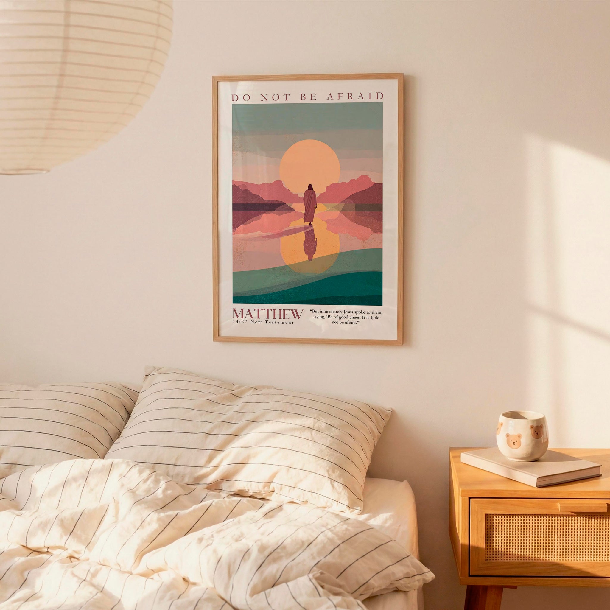 a bedroom scene with a framed poster of a sunset landscape hanging on the wall above a bed with striped bedding.