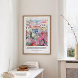 a framed poster of a colorful, floral-themed illustration hanging on a wall, with a quote from 1 Thessalonians 3:6 visible below the artwork.