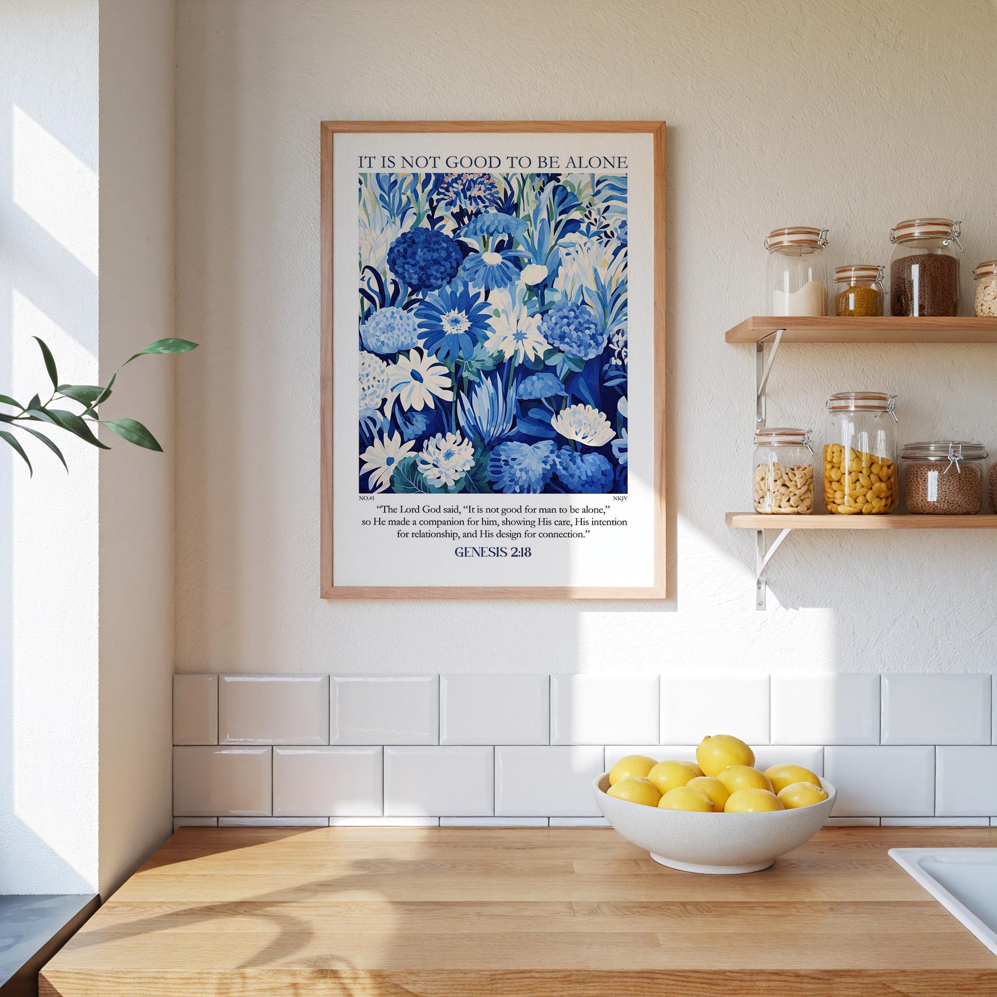 a kitchen scene with a framed poster of a blue floral pattern hanging on the wall above a wooden countertop with a bowl of lemons.