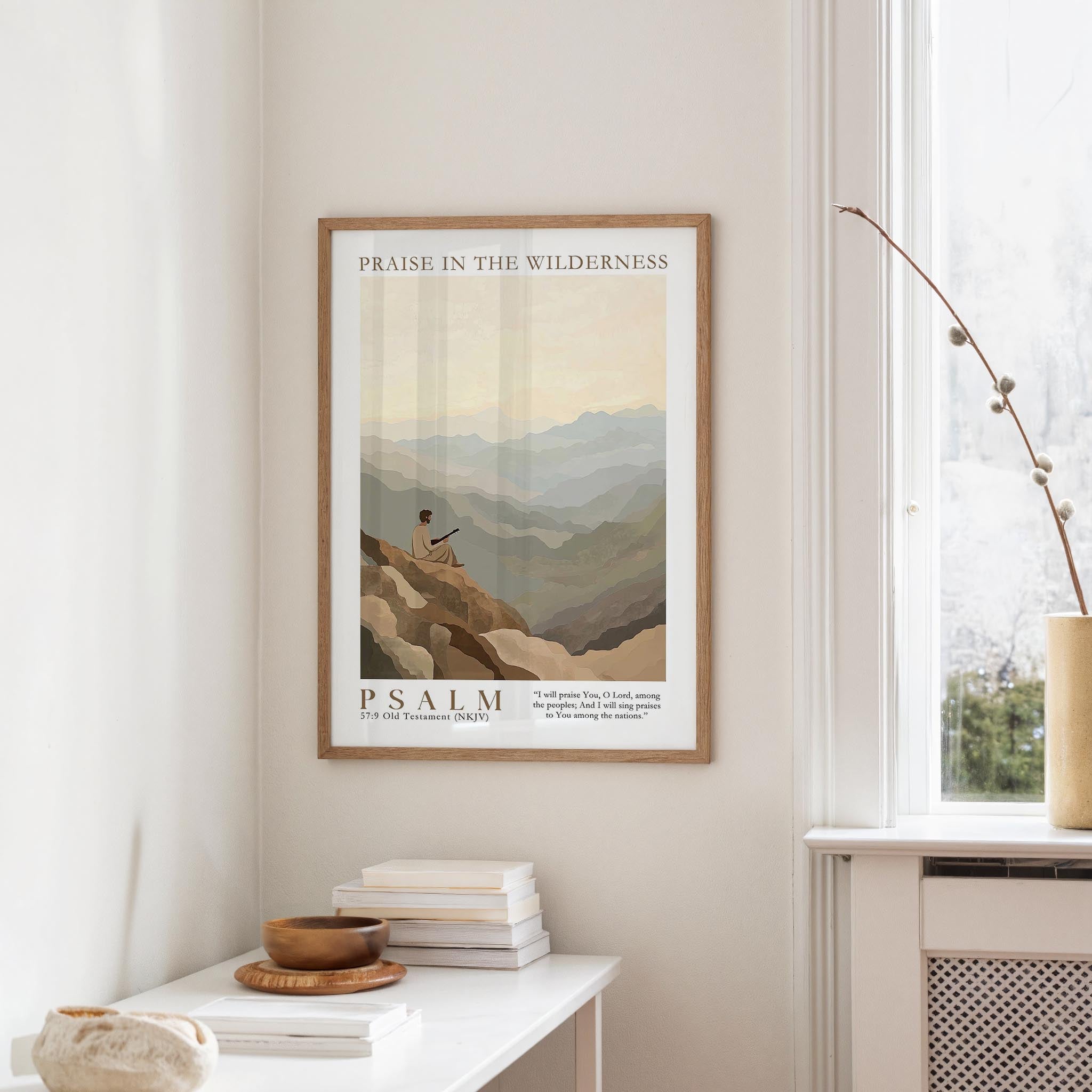 a framed poster of a mountain landscape hanging on a wall, with a window and a small table with books and a bowl on it below the poster.