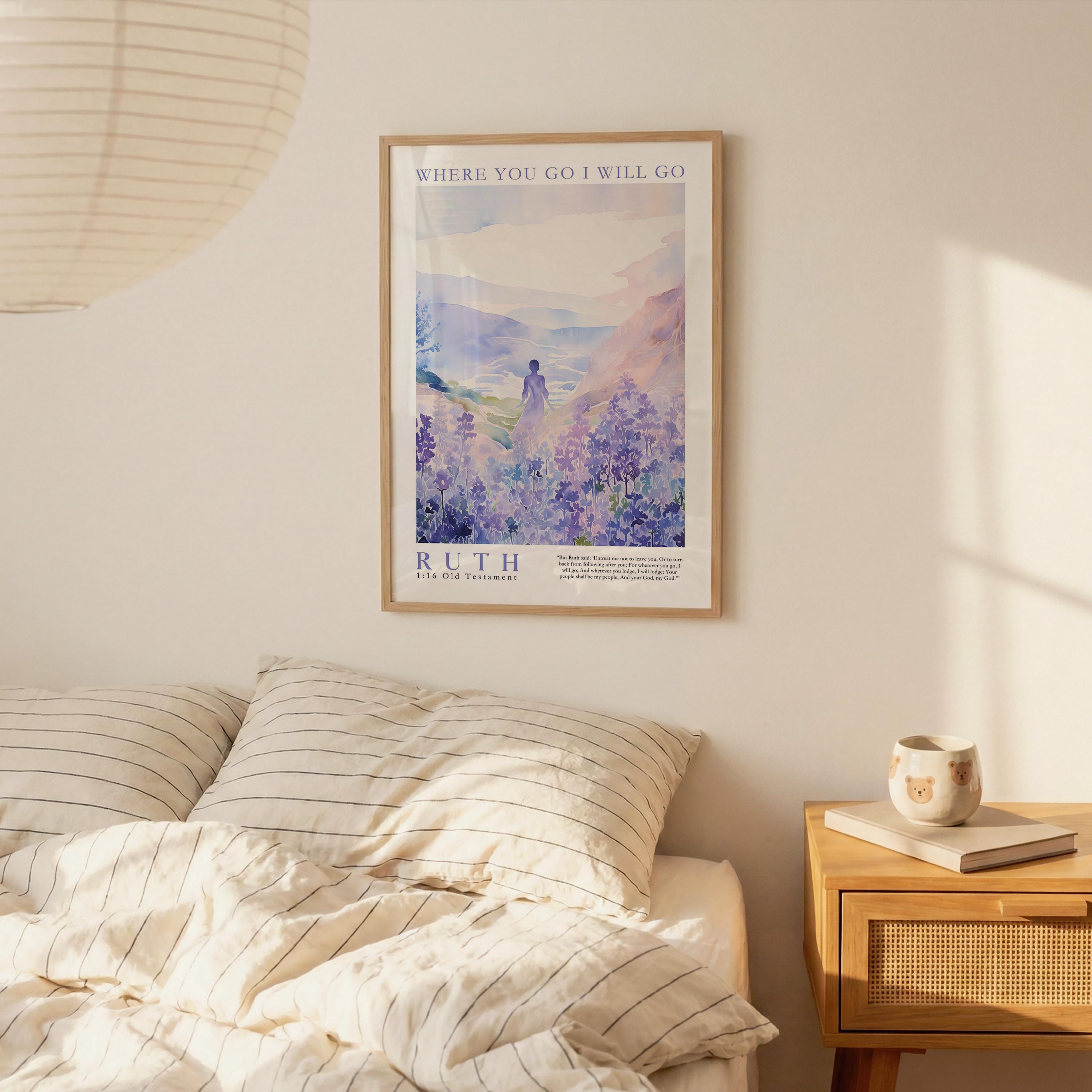 a bedroom scene with a framed poster of a woman in a field of flowers hanging on the wall above a bed with striped pillows.
