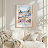 a framed poster of a colorful floral landscape hanging on a wall above a white couch with pillows.
