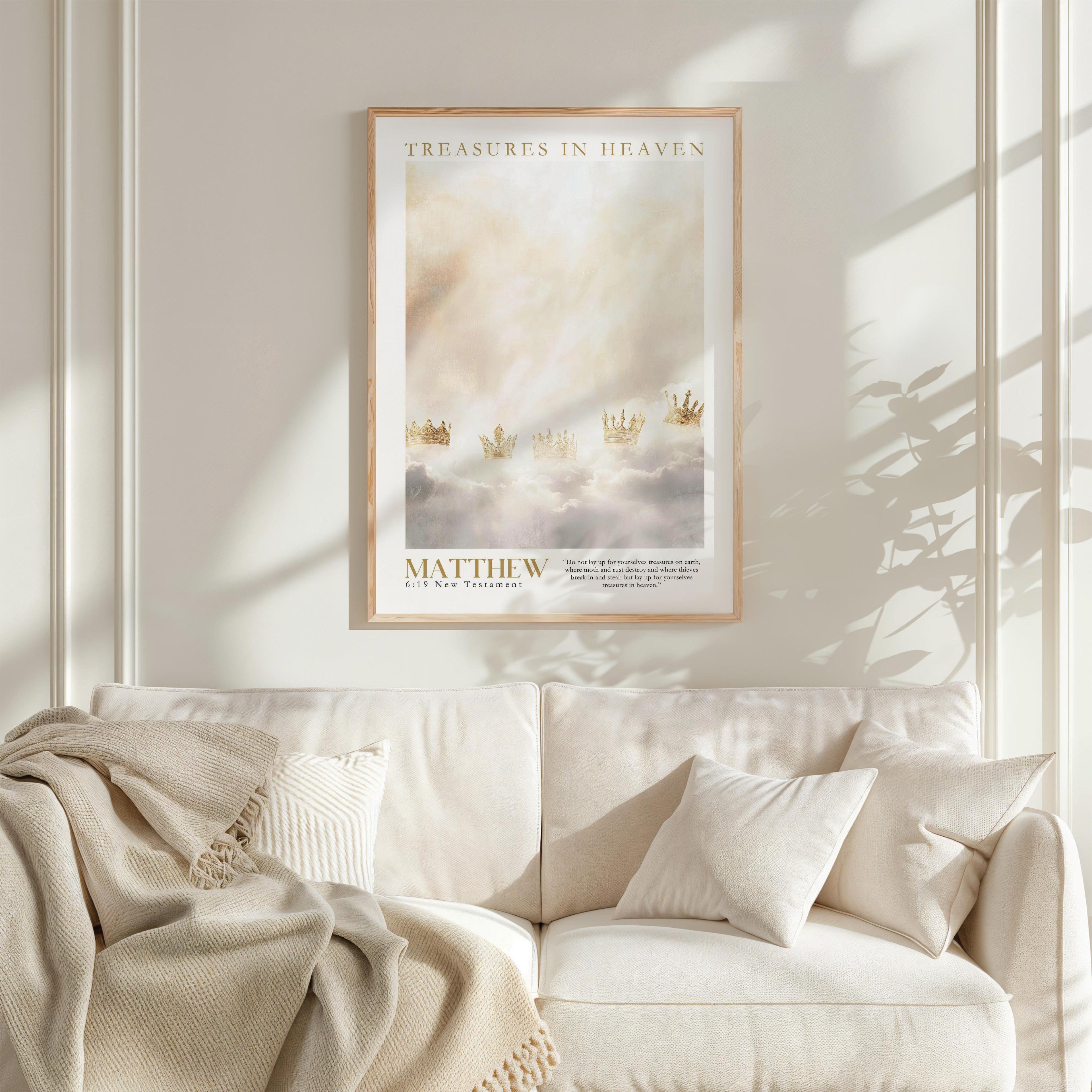 a framed poster of a serene landscape with clouds and a golden crown, hanging on a white wall above a white couch with a blanket draped over it.