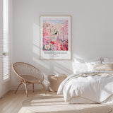 A bedroom with a large bed, a woven chair, and a framed poster of a garden scene on the wall.