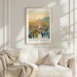 A framed poster of a large crowd of people, with a religious or biblical theme, hangs on a white wall above a white couch.