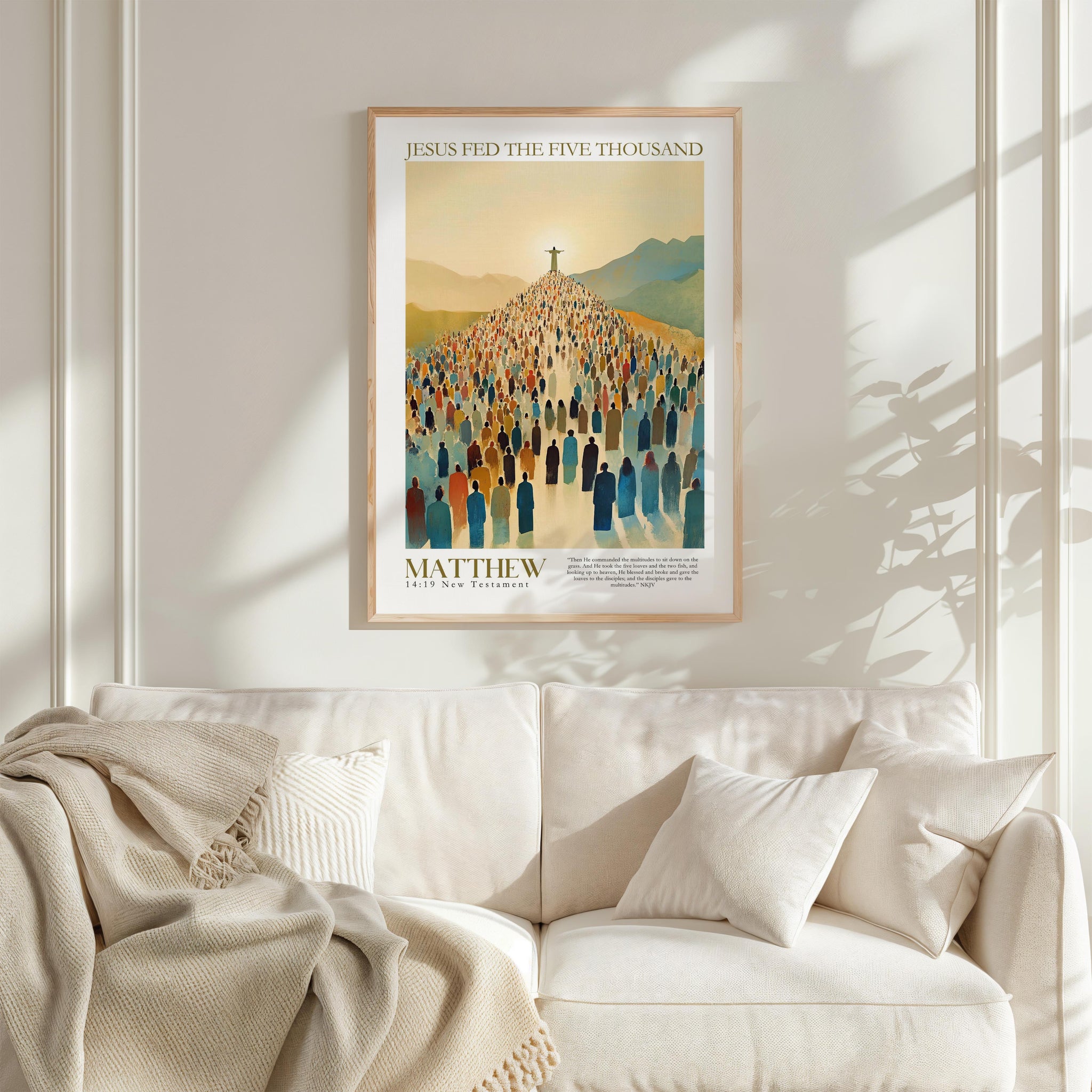 A framed poster of a large crowd of people, with a religious or biblical theme, hangs on a white wall above a white couch.