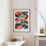 a colorful poster of birds hanging on a wall, with a stack of books and a vase on a table below it.