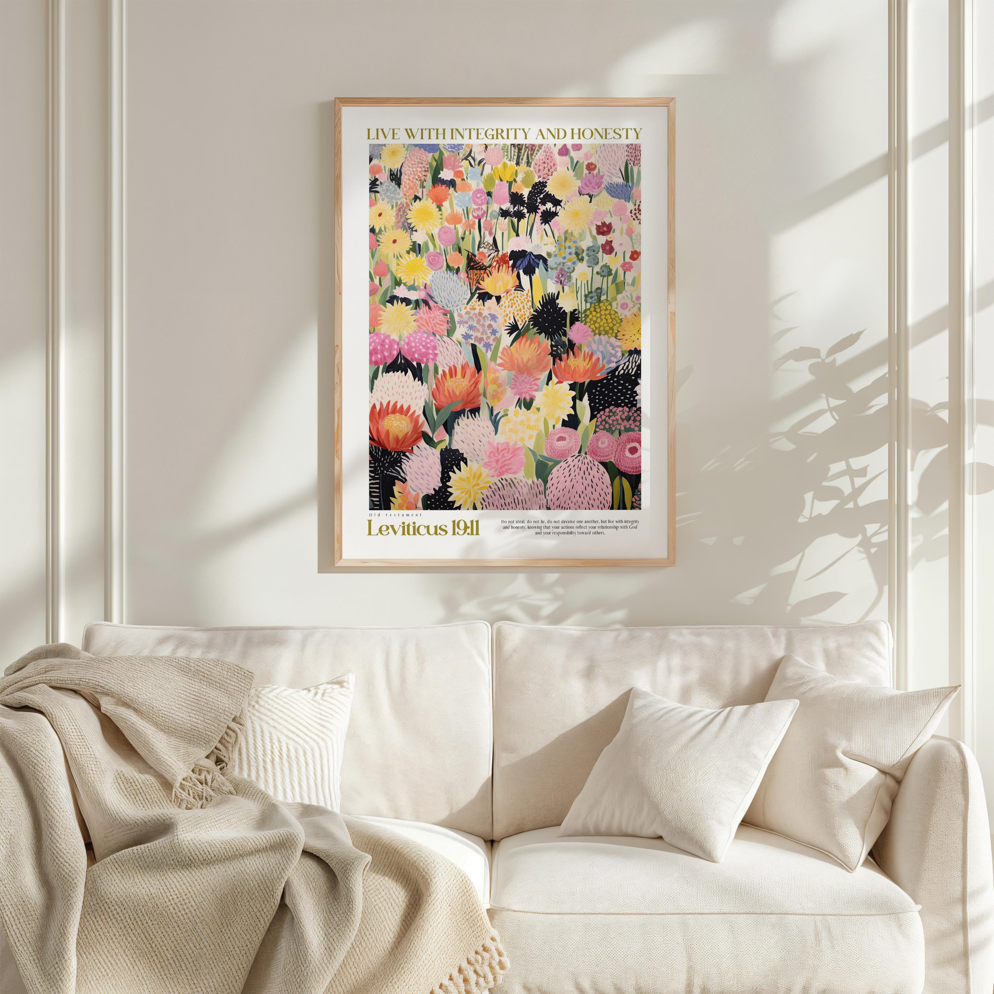 a framed poster of a colorful floral arrangement hanging on a wall above a white couch with pillows.