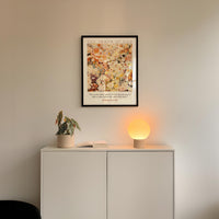 a white cabinet with a potted plant and a lamp on top, set against a white wall.