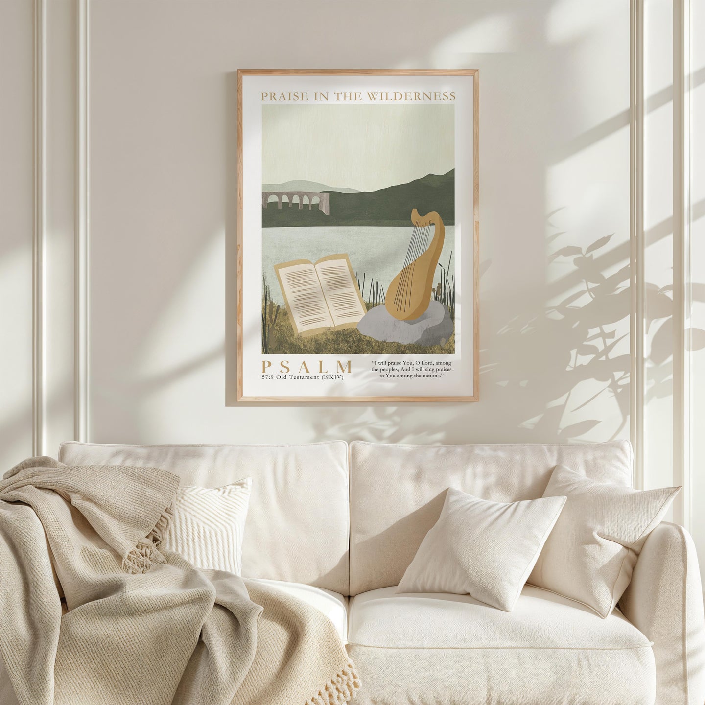a framed poster of a harp and an open book, hanging on a white wall above a white couch with a blanket draped over it.