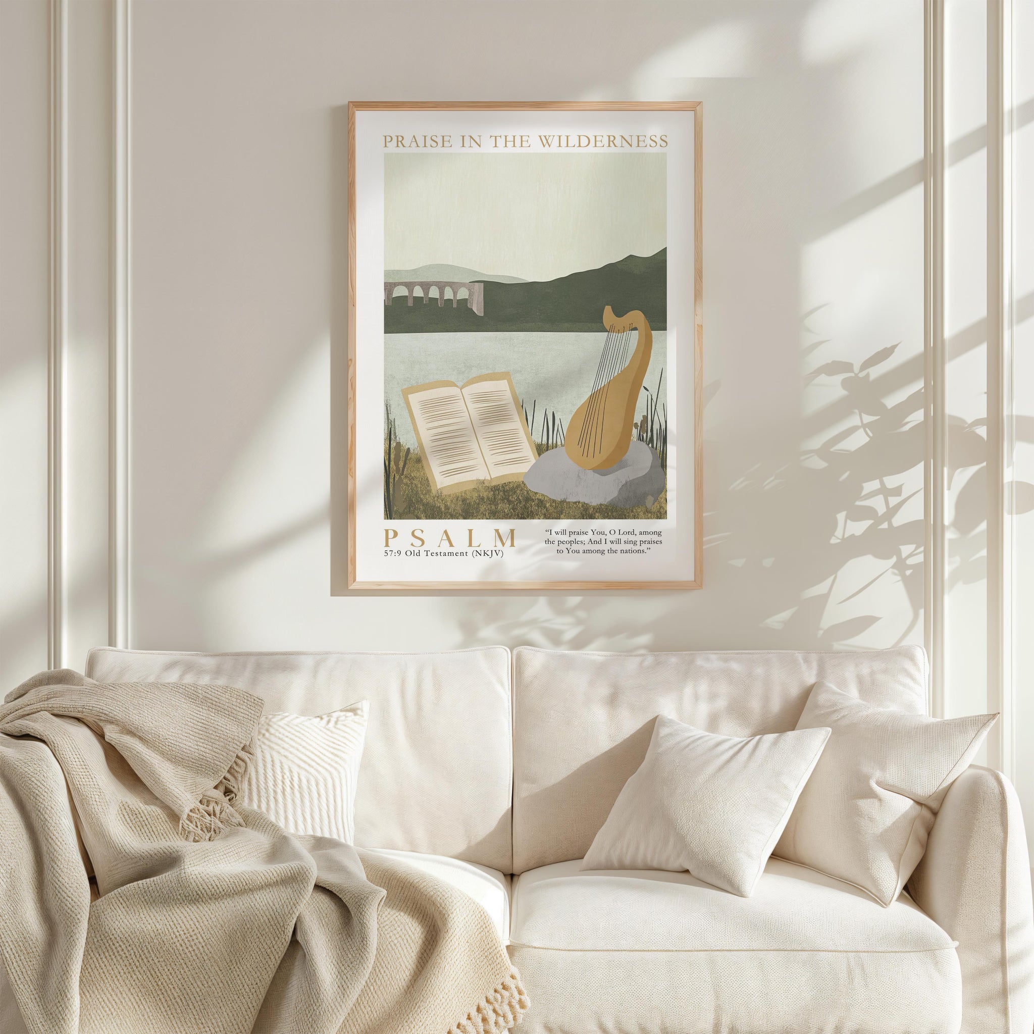 a framed poster of a harp and an open book, hanging on a white wall above a white couch with a blanket draped over it.