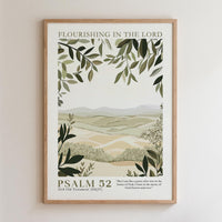The image is a framed poster with a landscape scene featuring mountains, trees, and greenery. The text on the poster reads "FLOURISHING IN THE LORD" and "PSALM 52" along with a Bible verse reference.