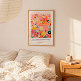 a bedroom setting with a bed, a nightstand, and a framed poster on the wall. The poster is a colorful illustration of flowers and includes a Bible verse from Isaiah 58:1-3.
