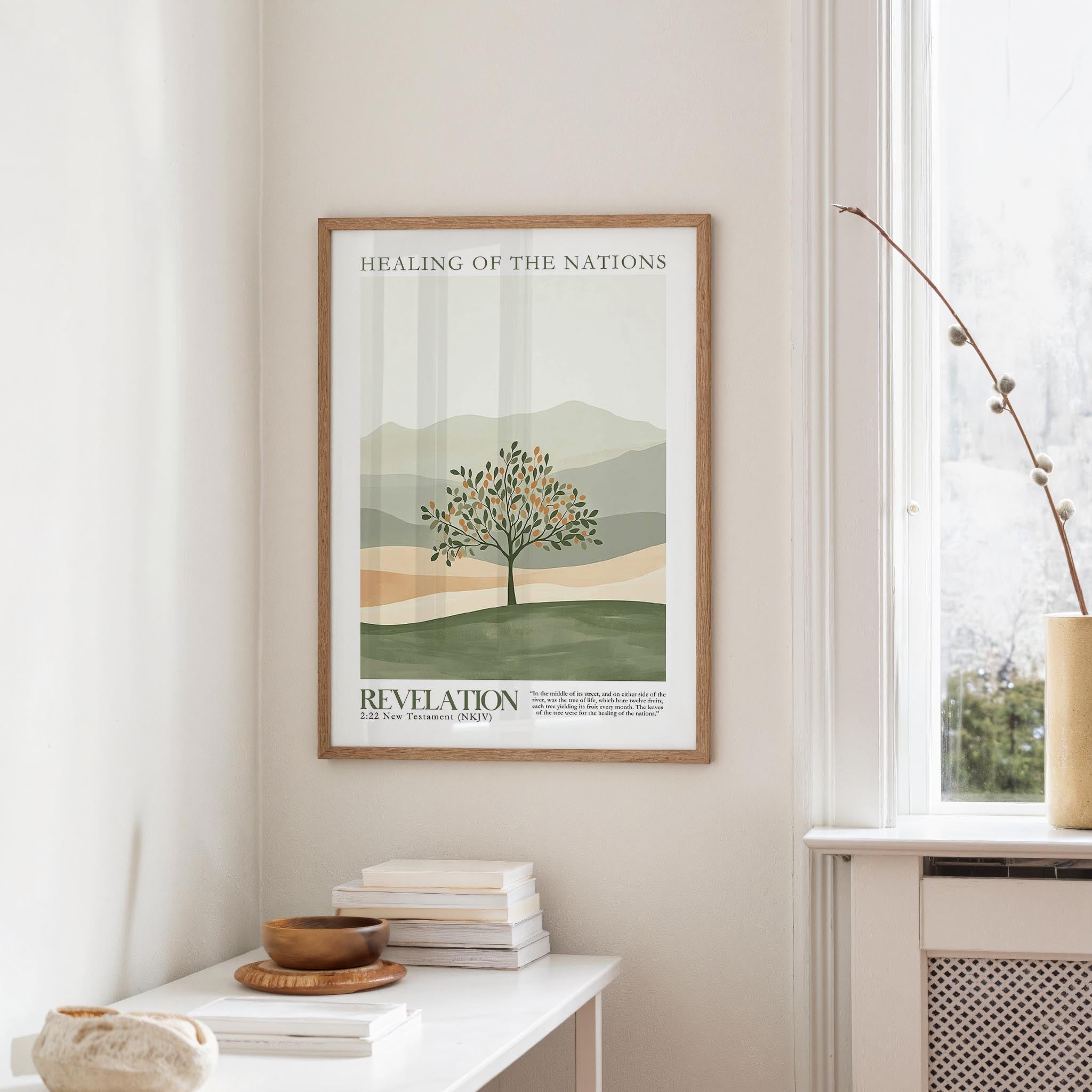 a framed poster of a tree with mountains in the background, hanging on a wall in a room with a white table and a window.