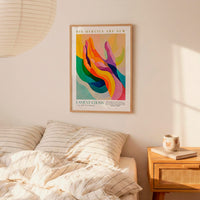 a poster of a colorful abstract design hanging on a wall above a bed with striped pillows.