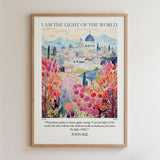 The image is a framed poster with a colorful illustration of a cityscape and flowers. The poster has a religious message and a Bible verse from John 8:12.