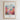 The image is a framed poster with a colorful illustration of a cityscape and flowers. The poster has a religious message and a Bible verse from John 8:12.