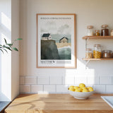 a kitchen counter with a bowl of lemons, a framed poster of a coastal scene, and a shelf with jars and bottles.