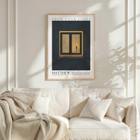 a framed poster of a candle in a window, hanging on a white wall above a white couch with a blanket draped over it.