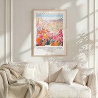 a cozy living room with a white sofa and a framed poster of a colorful floral scene hanging on the wall above it.
