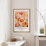 a framed poster of a vibrant floral design hanging on a wall, with a quote from the Bible below it.