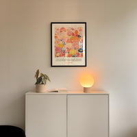 a white cabinet with a potted plant and a lamp on top, set against a white wall.