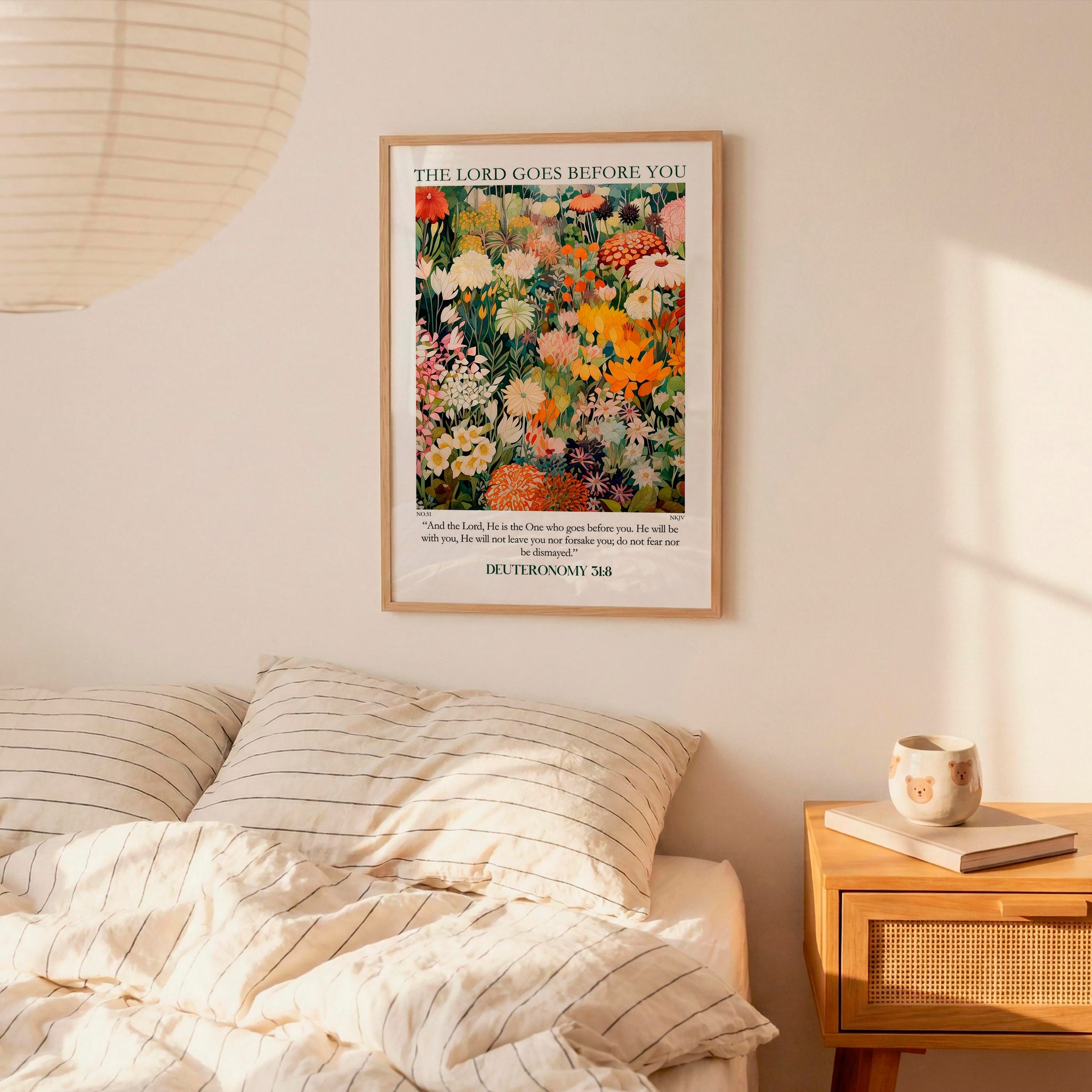 a bedroom scene with a framed poster of a colorful floral design hanging on the wall above a bed with striped pillows.