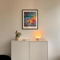 a white cabinet with a plant and a lamp on top, and a framed poster of a colorful abstract landscape hanging on the wall above the cabinet.