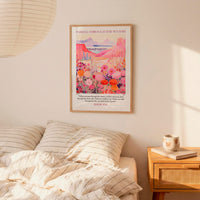 a bedroom scene with a framed poster of a colorful landscape hanging on the wall above a bed with striped pillows.