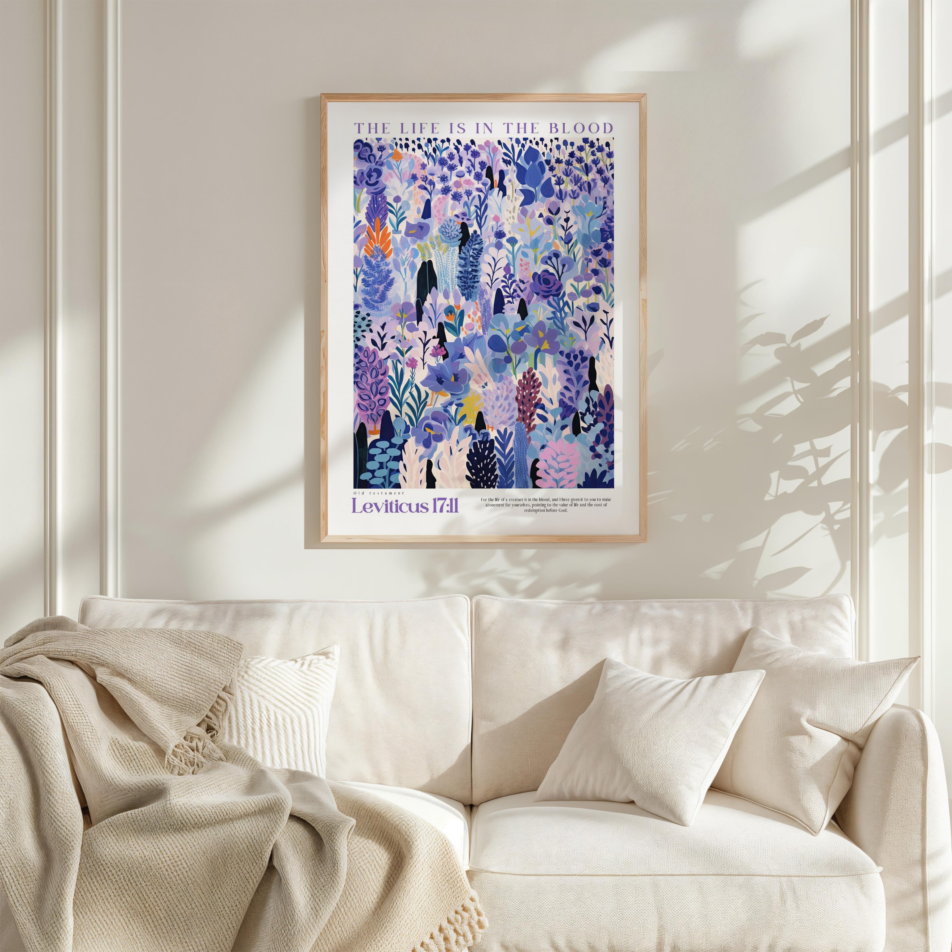 a framed poster of a colorful floral illustration hanging on a white wall above a white couch with a blanket draped over it.