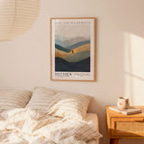 a bedroom setting with a framed poster of a mountain landscape hanging on the wall above a bed with striped bedding.