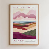 The image is a framed poster featuring a landscape with hills and mountains in various shades of pink, purple, and green. The text above the poster reads "HE WILL GUIDE YOU" and below the poster is the biblical verse " Isaiah 51:11 Old Testament (NKJV)", which translates to "The Lord will guide you continually, And satisfy your end in drought".