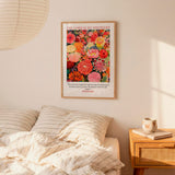 a bedroom scene with a framed poster of a colorful floral design hanging on the wall above a bed with striped pillows.