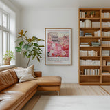 a cozy living room with a large bookshelf filled with books, a comfortable leather couch, and a framed poster of a building with pink flowers hanging on the wall.