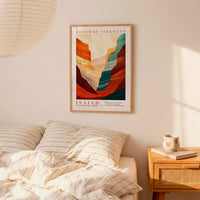 a bedroom setting with a framed poster of a mountain landscape hanging on the wall above a bed with striped bedding.