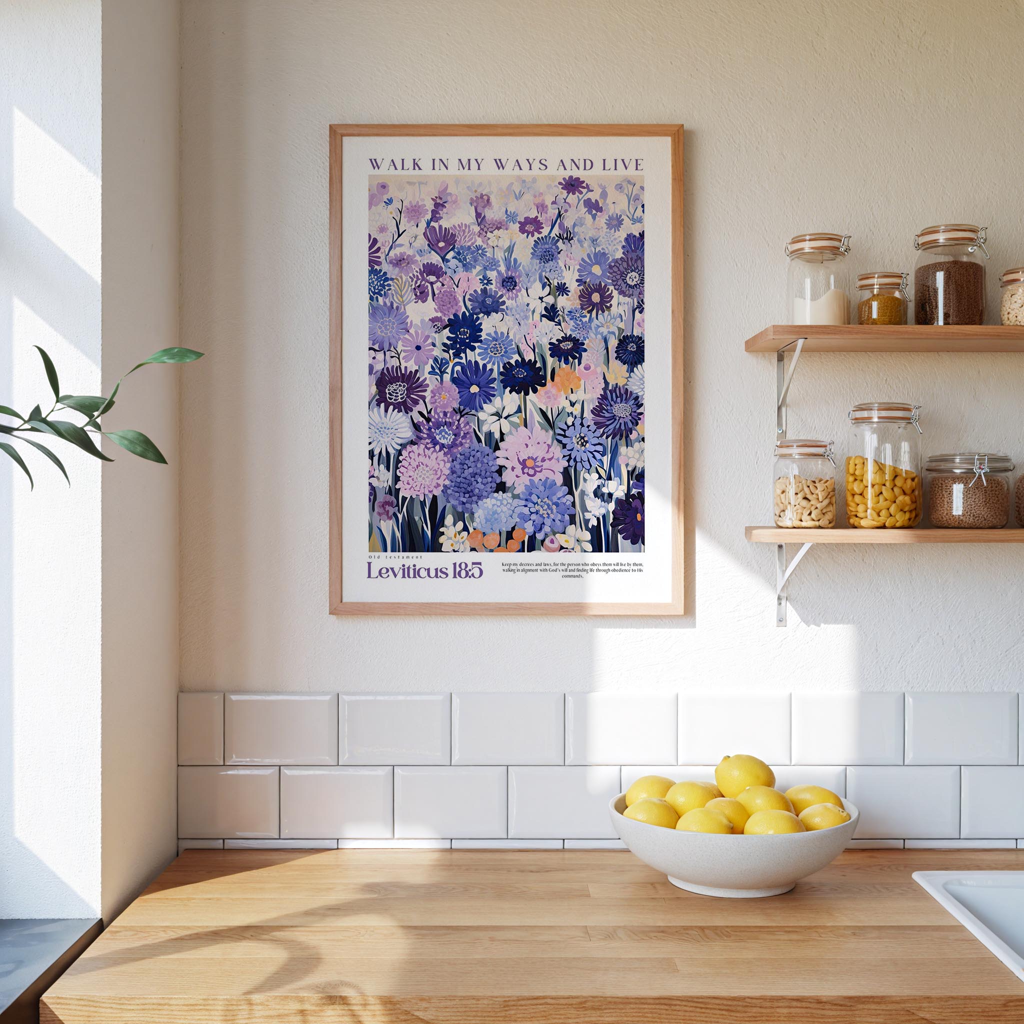 a kitchen scene with a framed poster of a flowery design hanging on the wall above a wooden countertop with a bowl of lemons.