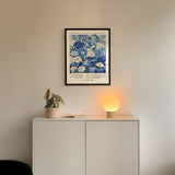 a white cabinet with a potted plant and a lamp on top, set against a white wall.