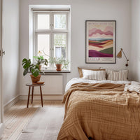A cozy bedroom with a large bed, a wooden nightstand, and a window with a plant on the sill. The room has a warm, inviting atmosphere with a colorful poster on the wall and a rug on the floor.