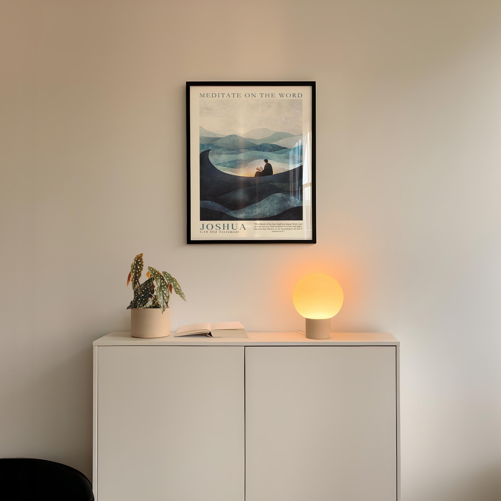 a minimalist interior design with a framed poster of a landscape, a potted plant, and a small lamp on a white cabinet.