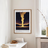 a framed poster of a dramatic landscape with a large explosion in the center, hanging on a wall above a white table with a stack of books and a small vase.