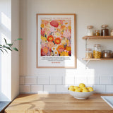 a kitchen scene with a framed poster of a colorful floral design hanging on the wall above a wooden countertop with a bowl of lemons.