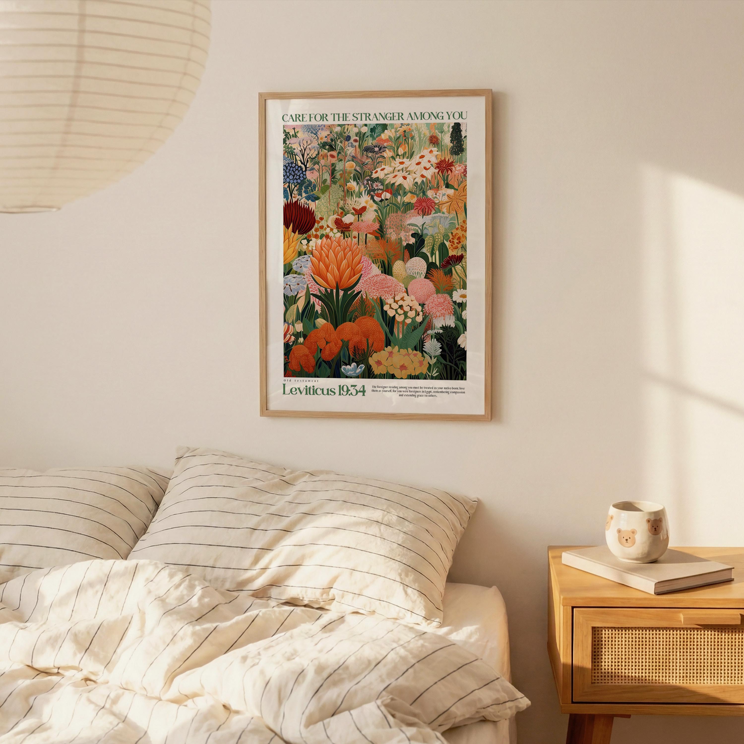a framed poster of a colorful floral arrangement hanging on a wall above a bed with striped pillows.
