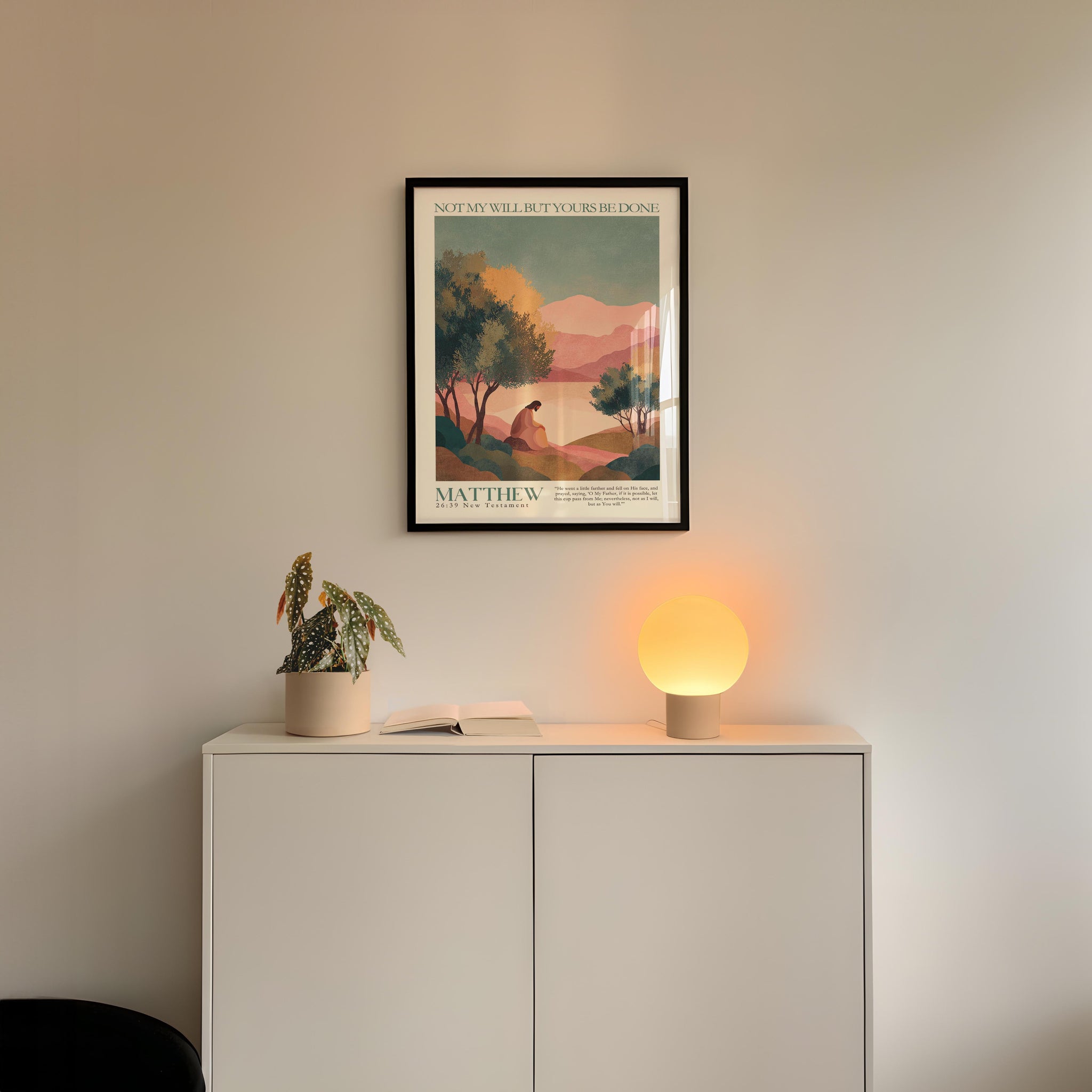 a minimalist interior design with a framed poster of a landscape, a potted plant, and a small lamp on a white cabinet.