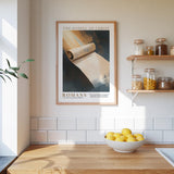 a kitchen counter with a bowl of lemons, a framed poster of a scroll, and a shelf with jars and other kitchen items.