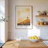 A framed poster of a lighthouse on a wall, with a bowl of lemons and a shelf of jars below it, in a kitchen setting.