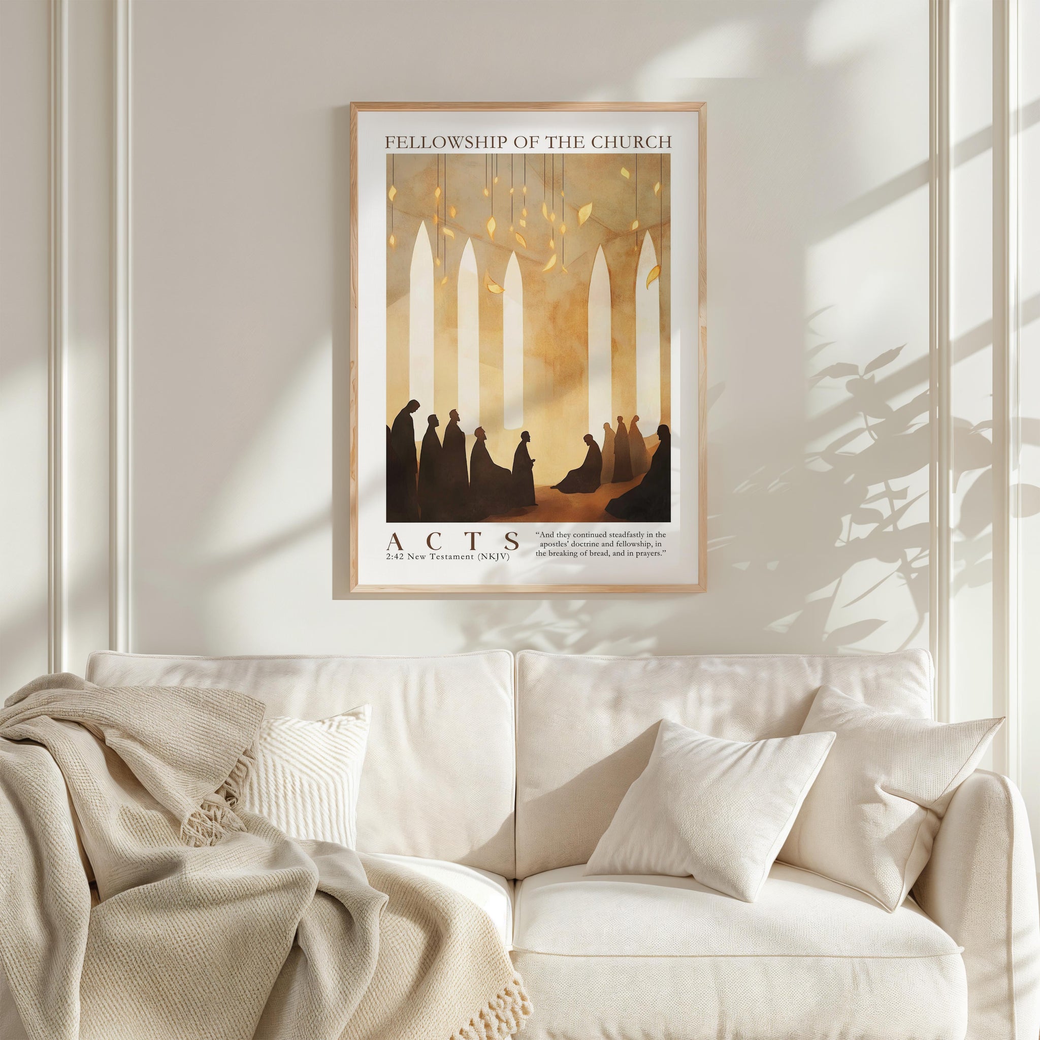 a framed poster of a group of people in a church setting, hanging on a wall above a white couch with a blanket draped over it.