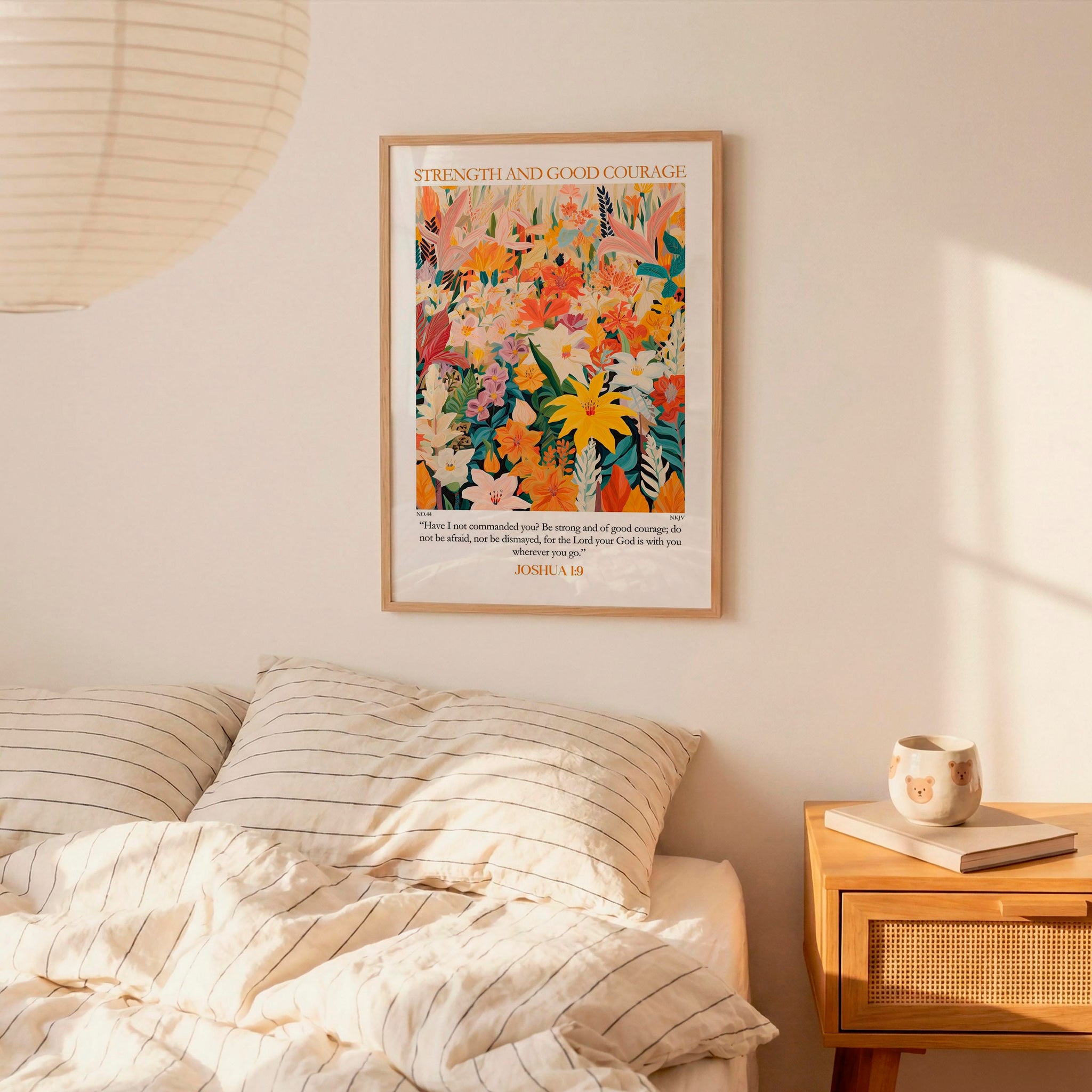 a bedroom setting with a bed, a nightstand, and a poster on the wall. The poster is a colorful floral design with the text "STRENGTH AND GOOD COURAGE" and "JOSIA 19" below it.