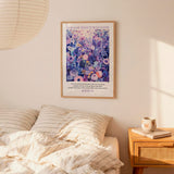 a bedroom scene with a framed poster of a colorful floral design hanging on the wall above a bed with striped pillows.