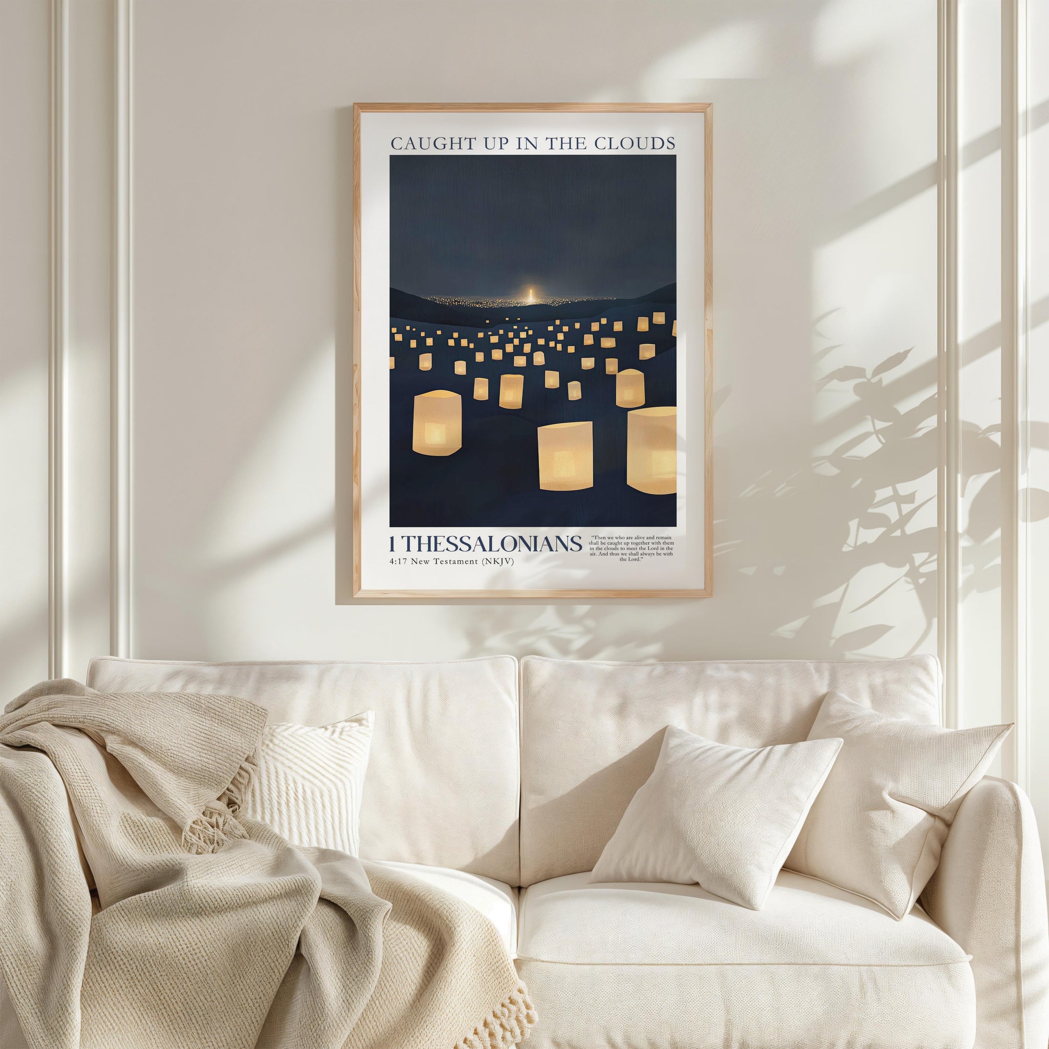 a framed poster of a nighttime scene with numerous lit lanterns, hanging on a wall above a white couch with a blanket draped over it.