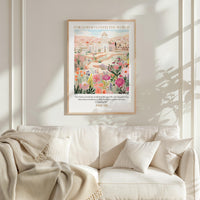 a cozy living room with a white sofa and a framed poster of a cityscape with flowers hanging on the wall above it.